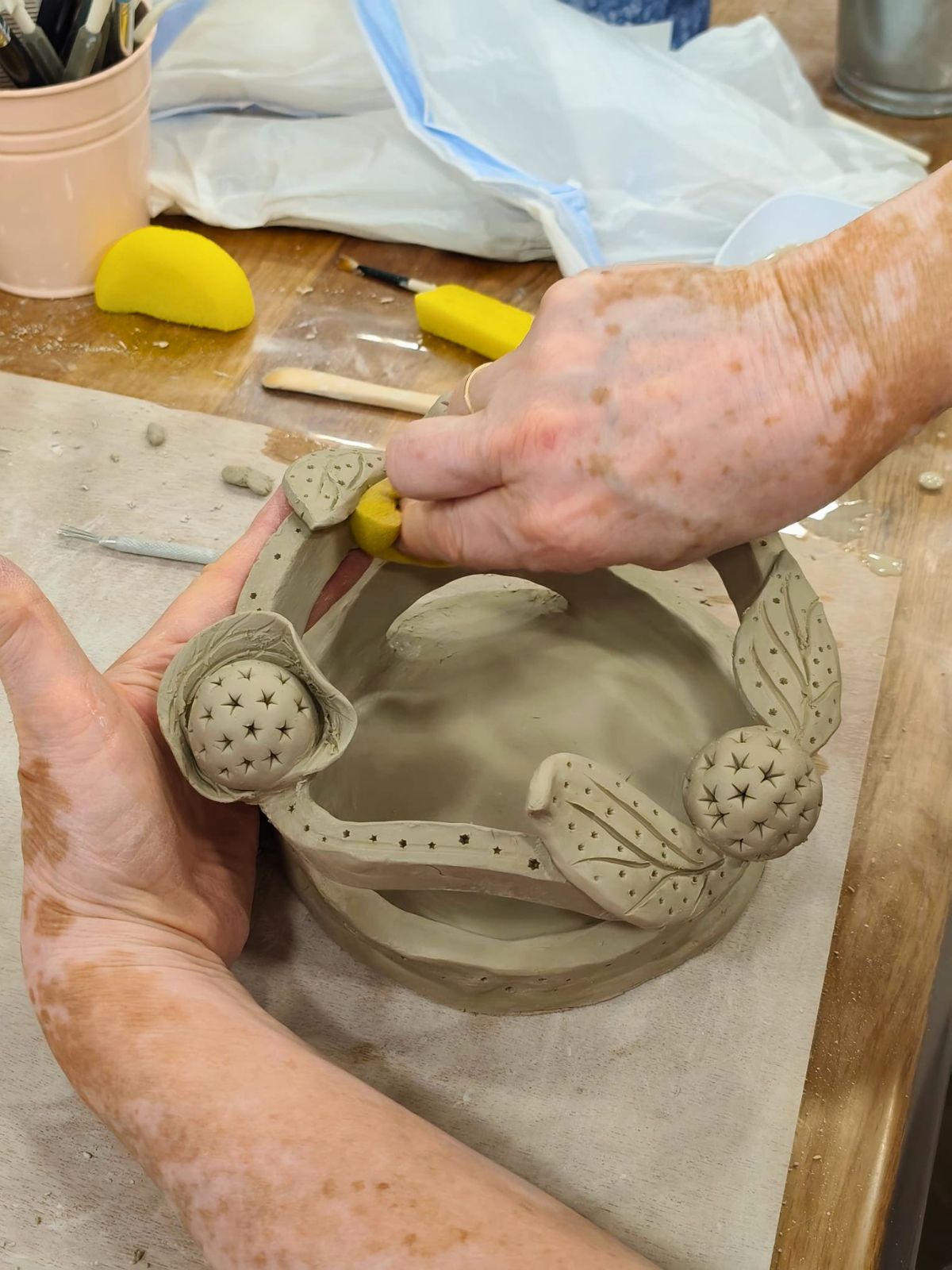 Primer plano de manos dando textura a una pieza de cerámica hecha a mano